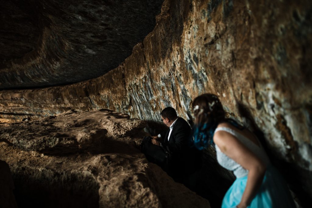 Bride and groom scooting through a cave at Hamilton Pool. 
