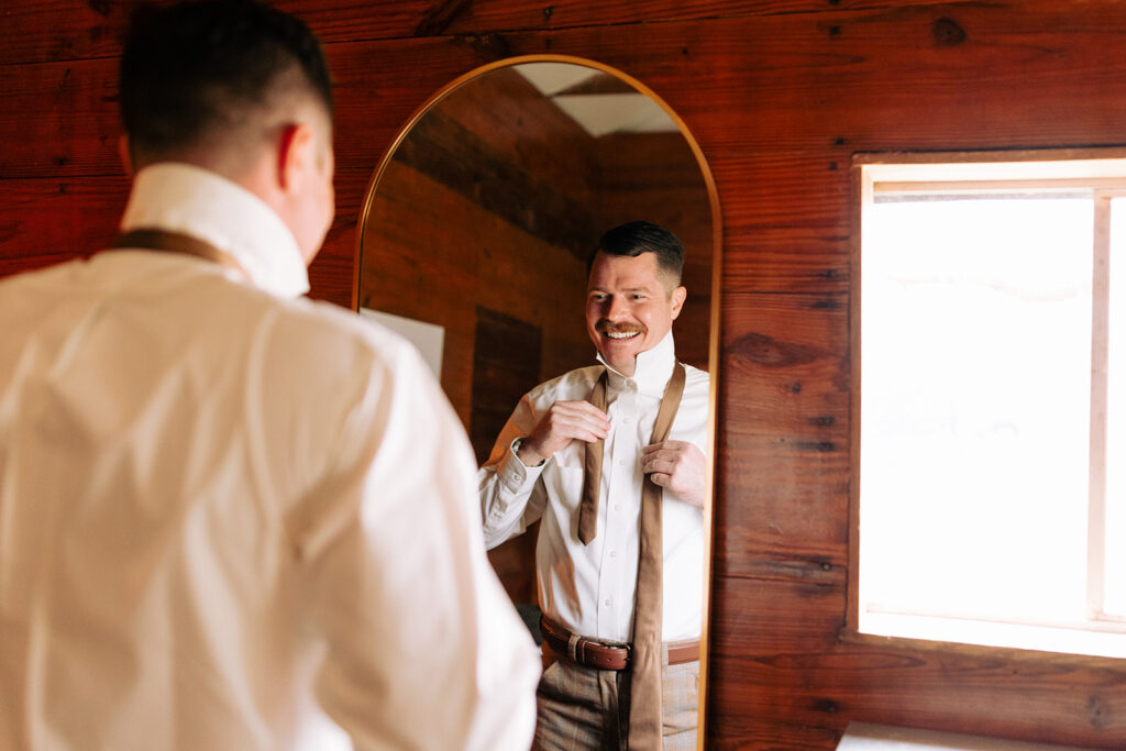 groom gets ready in cabin on wedding day