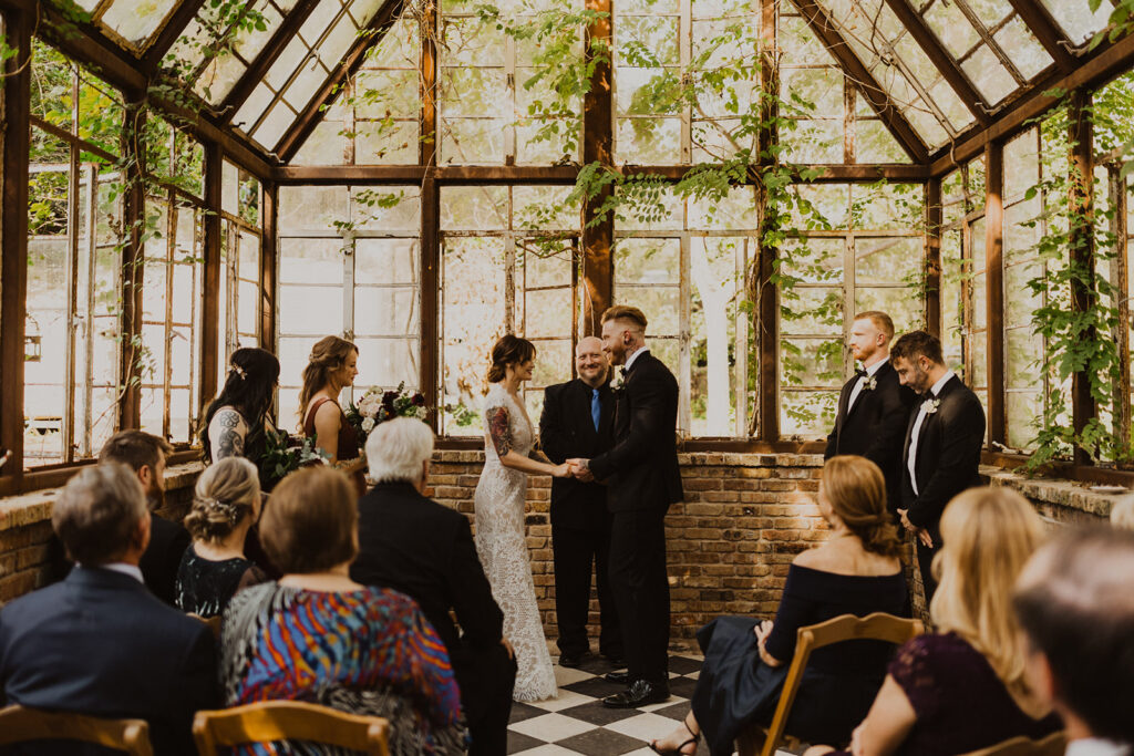 couple exchanges vows at Sekrit Theater vintage greenhouse wedding