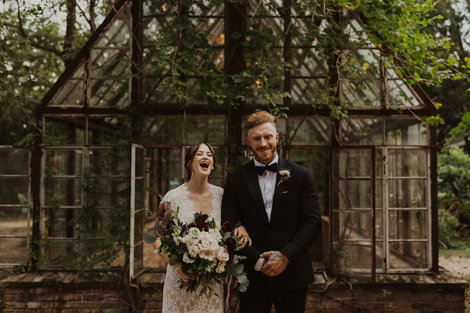 couple stands in front of vintage greenhouse wedding venue