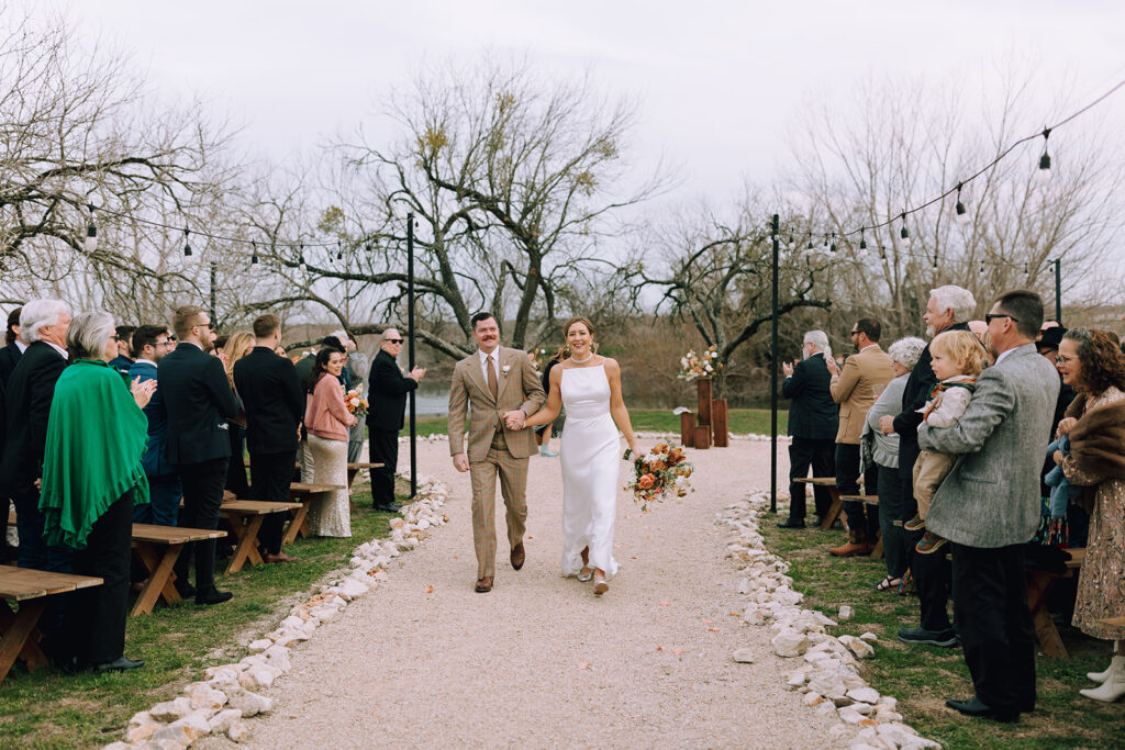 couple walks hand in hand from outdoor wedding ceremony