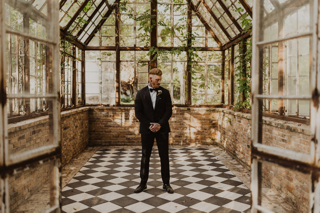 groom stands in Sekrit Theater vintage greenhouse 