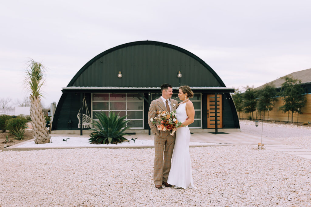 couple stands in front of Austin wedding venue 