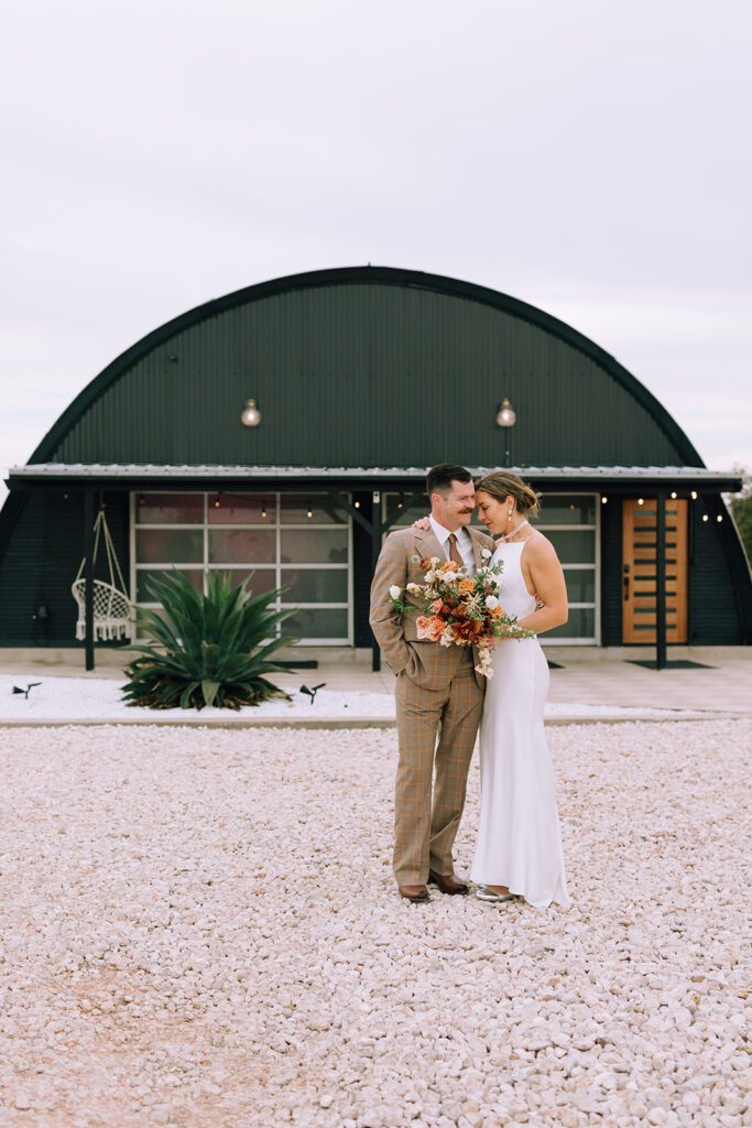 couple embraces outside of Camino Real Ranch greenhouse wedding venue