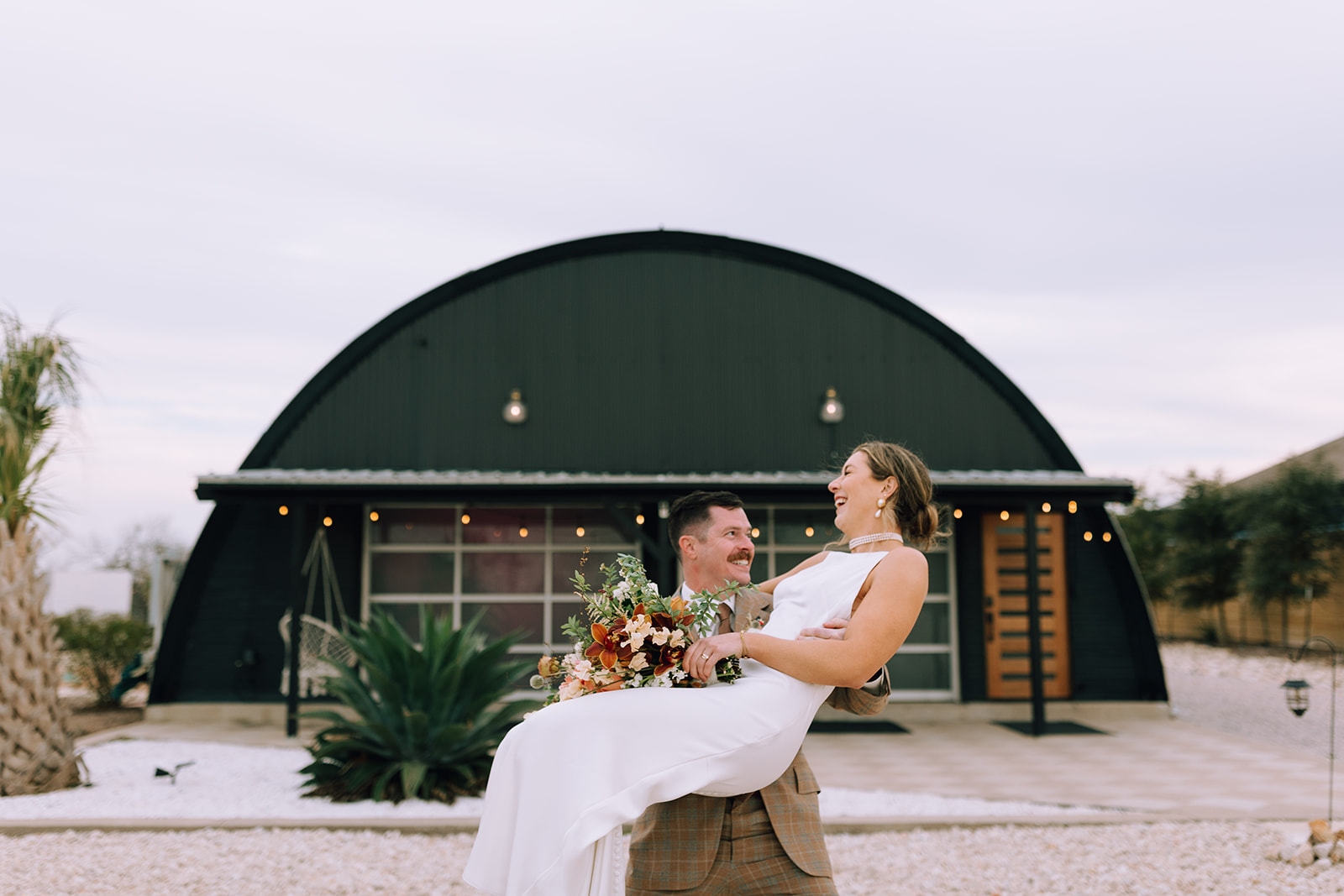 couple embraces in front of Texas wedding venue