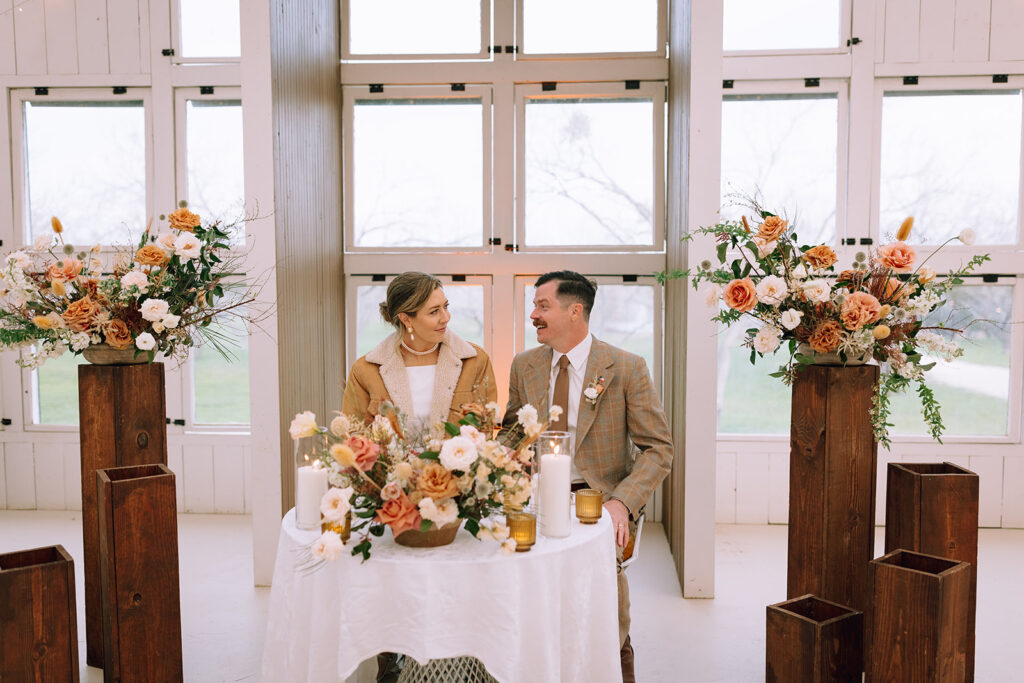 couple sits at floral wedding table