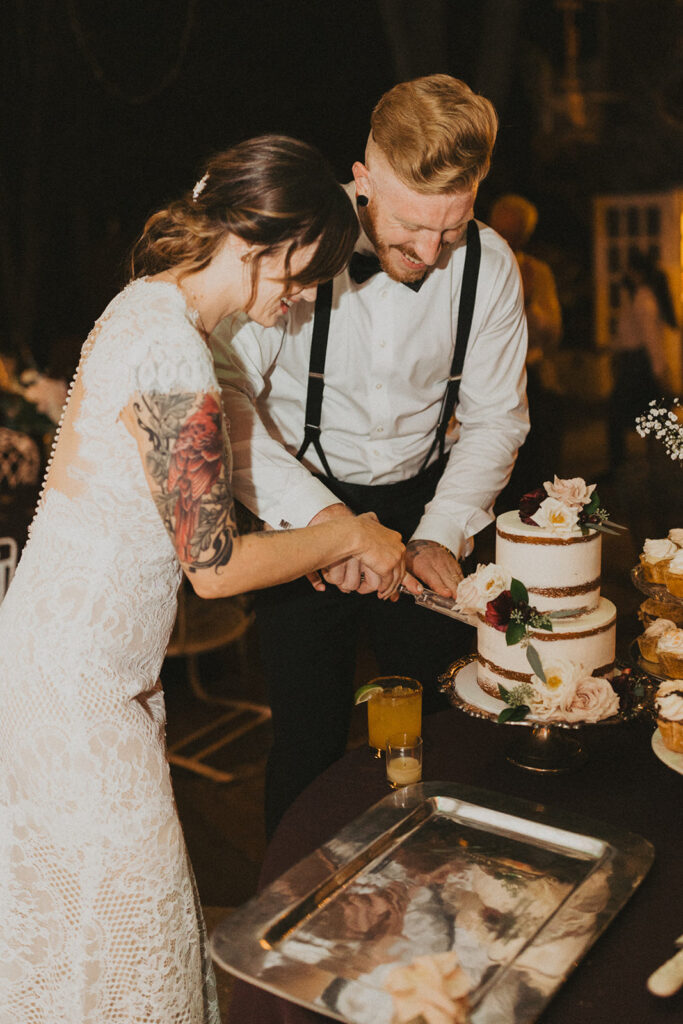 couple cuts the cake at Sekrit Theater vintage greenhouse 