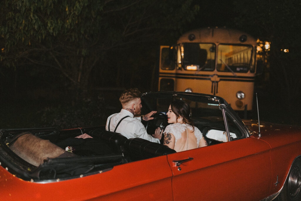 couple drives in red car to sparkler wedding exit