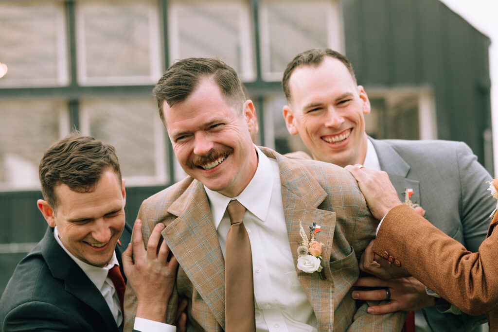 groomsmen laugh with groom on wedding day