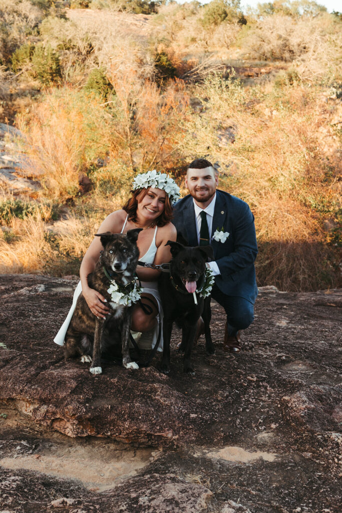couple poses with dog in sunset field