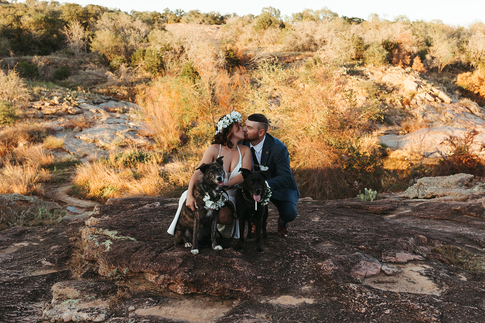 couple kisses with dogs at Inks Lake in Texas