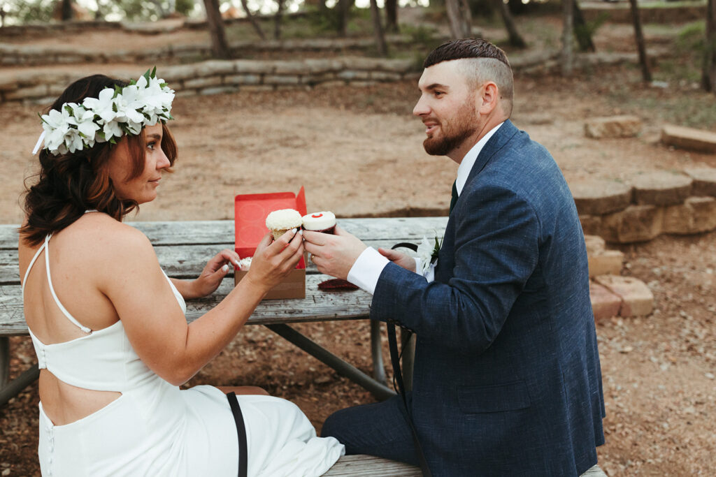 couple cheers with cupcakes at outdoor elopement