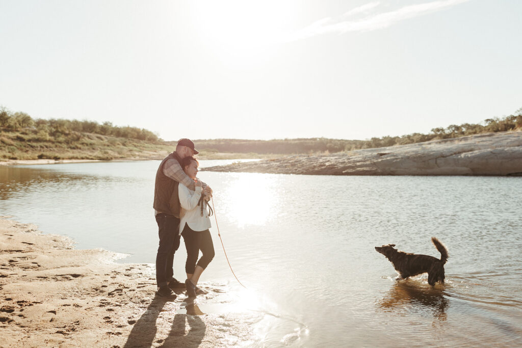 couple embraces with dogs at Inks Lake in Texas
