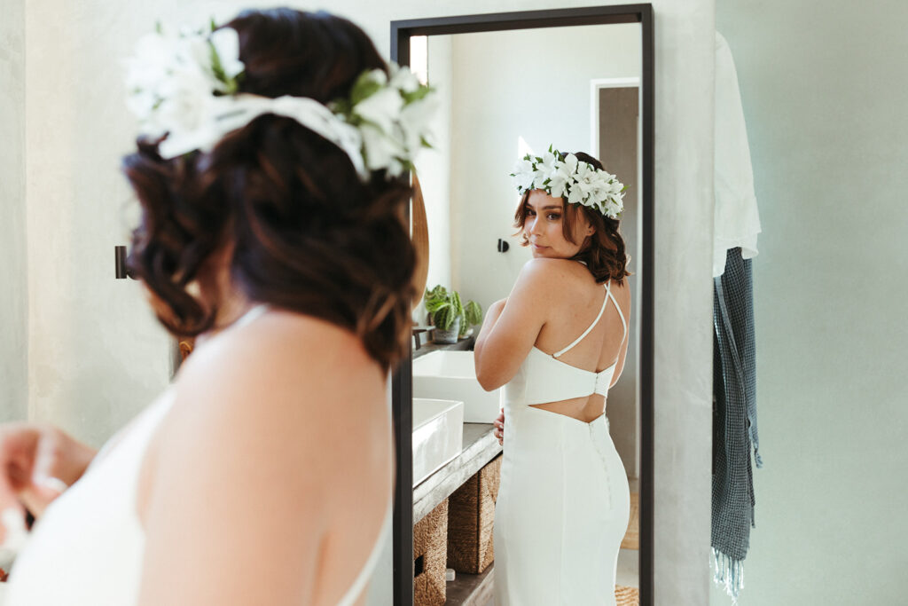 bride looks into mirror getting ready on wedding day