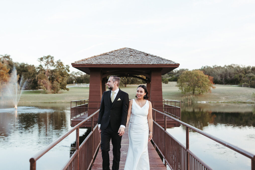 couple holds hands on dock over lake at outdoor Central Texas wedding