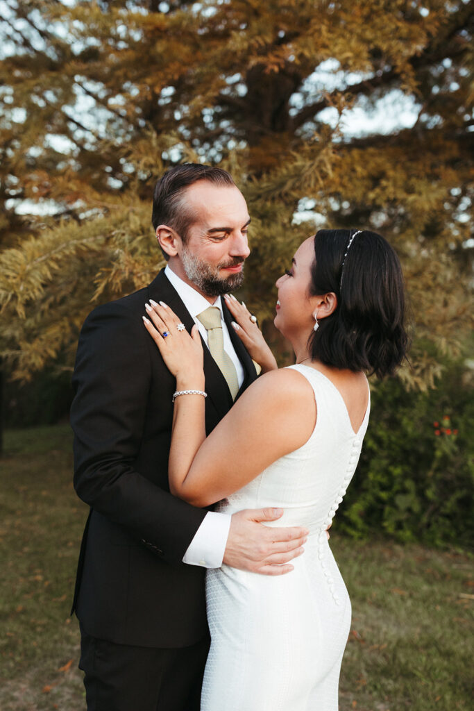 couple embraces under fall trees at outdoor wedding