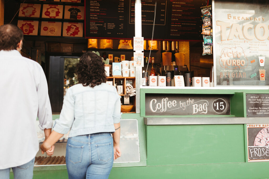 couple holds hands and orders coffee at Joe's coffee Austin