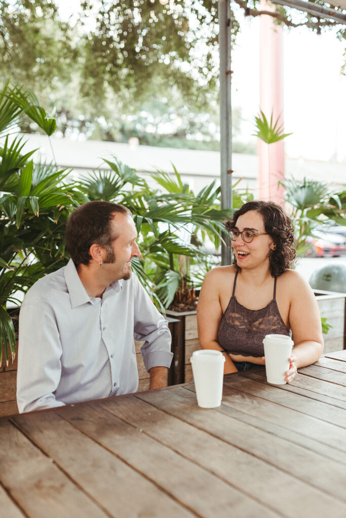 couple laughs while drinking coffee at engagement session