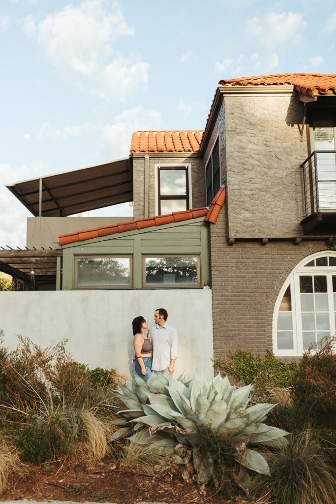couple stands in front of house at sunrise engagement session