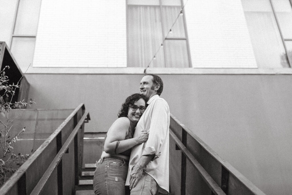 couple embraces standing on staircase at engagement session