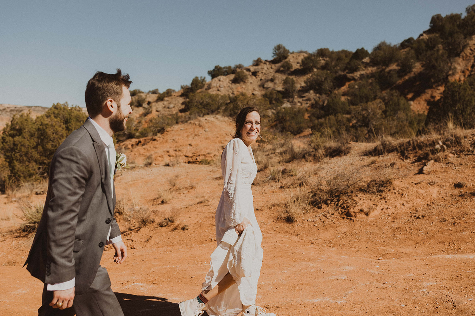 couple walks along desert path at sunrise elopement