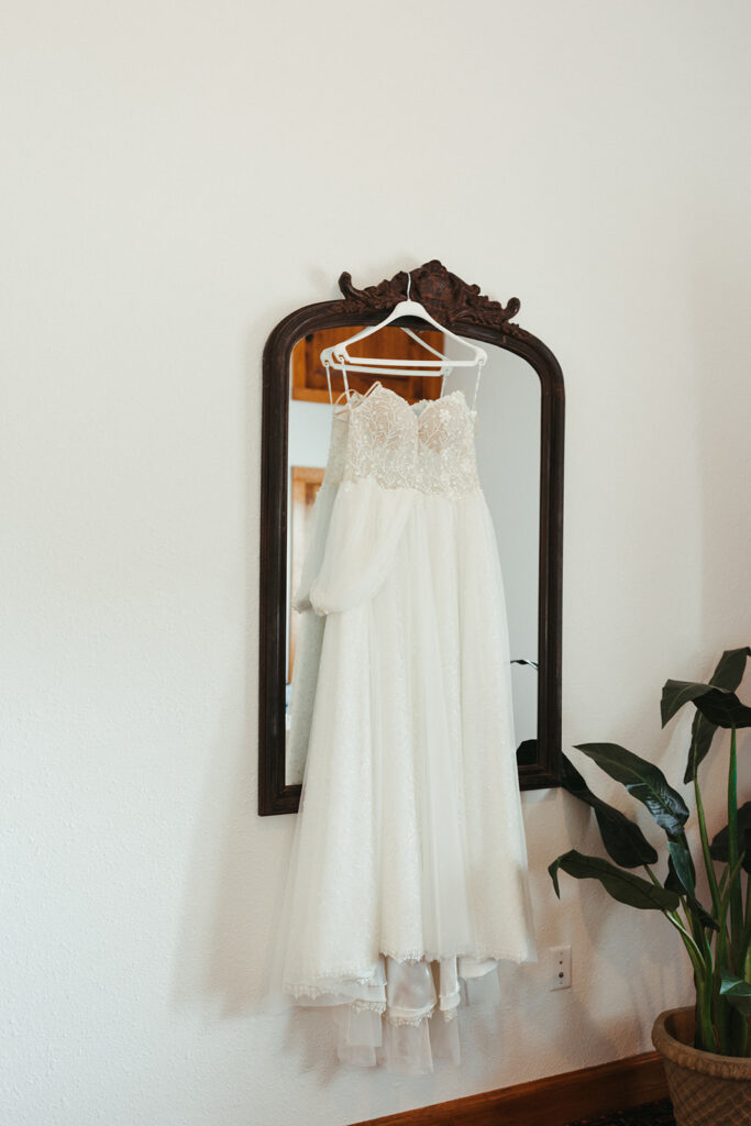 white wedding dress hangs on mirror 
