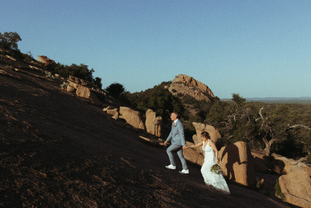couple walks up enchanted rock mountain at sunset elopement 