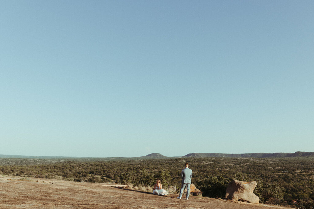 couple looks at texas hill country from enchanted rock overlook