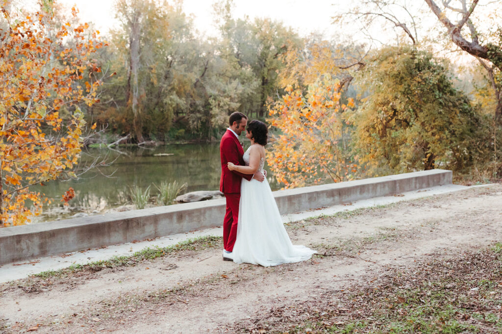 couple embraces along river at Shiraz Garden in Texas