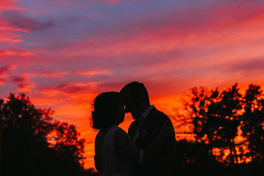 couple embraces under pink sky at sunset wedding 