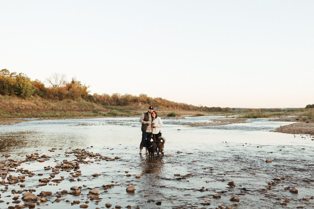couple embraces at beside lake at sunrise elopement