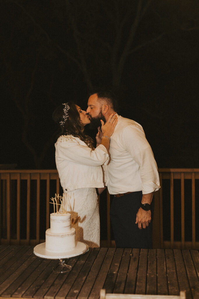 couple kisses beside cake during elopement reception