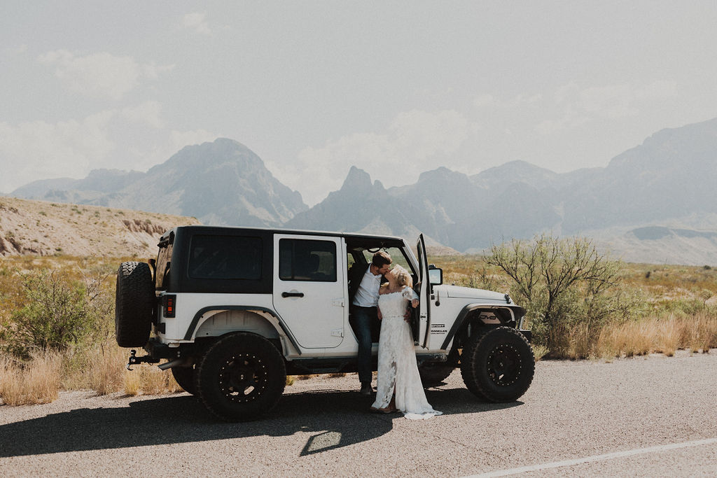 couple kisses beside Jeep during adventure elopement