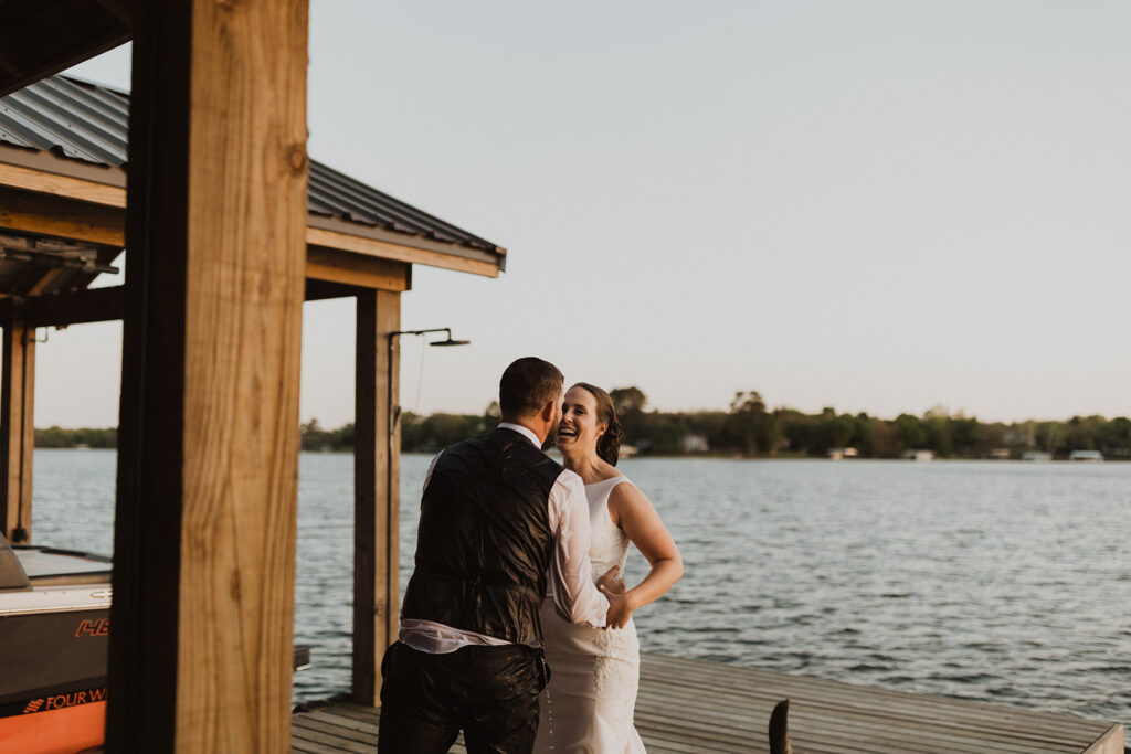 couple hugs after jumping into lake in wedding clothes