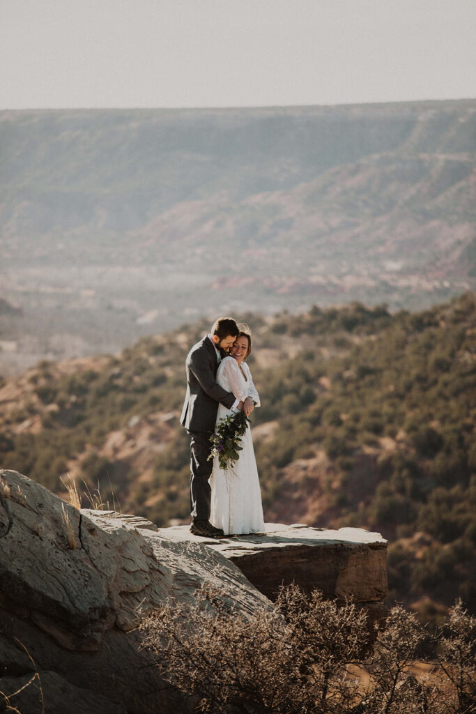 couple embraces on cliffside over green valley